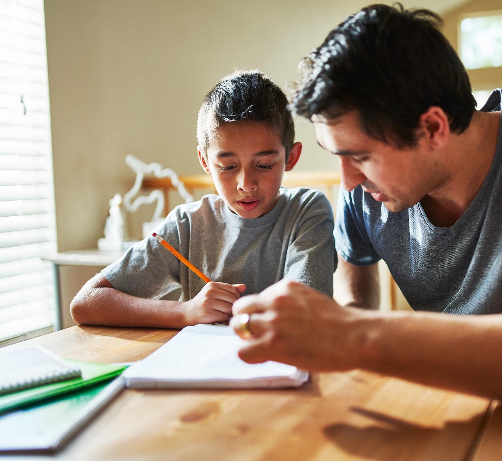 father helping boy with his homework at the kitchen table