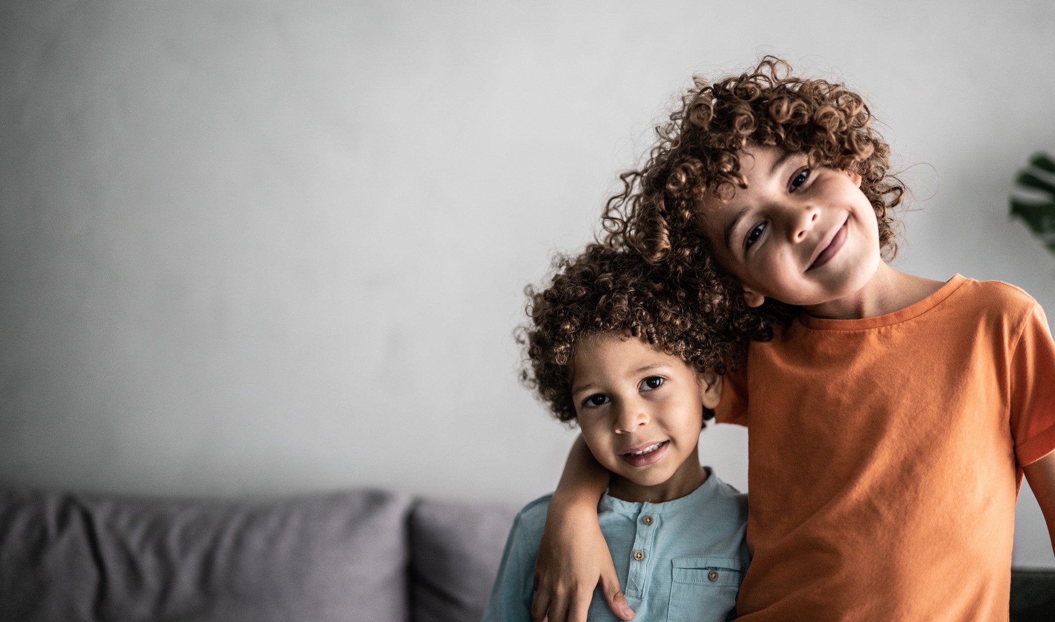 two smiling brothers with an arm around each other
