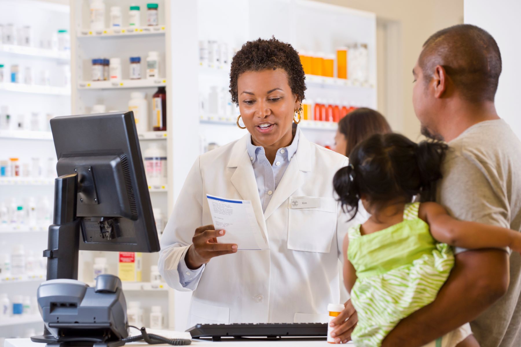 Father and young daughter in drugstore getting advice from female pharmacist