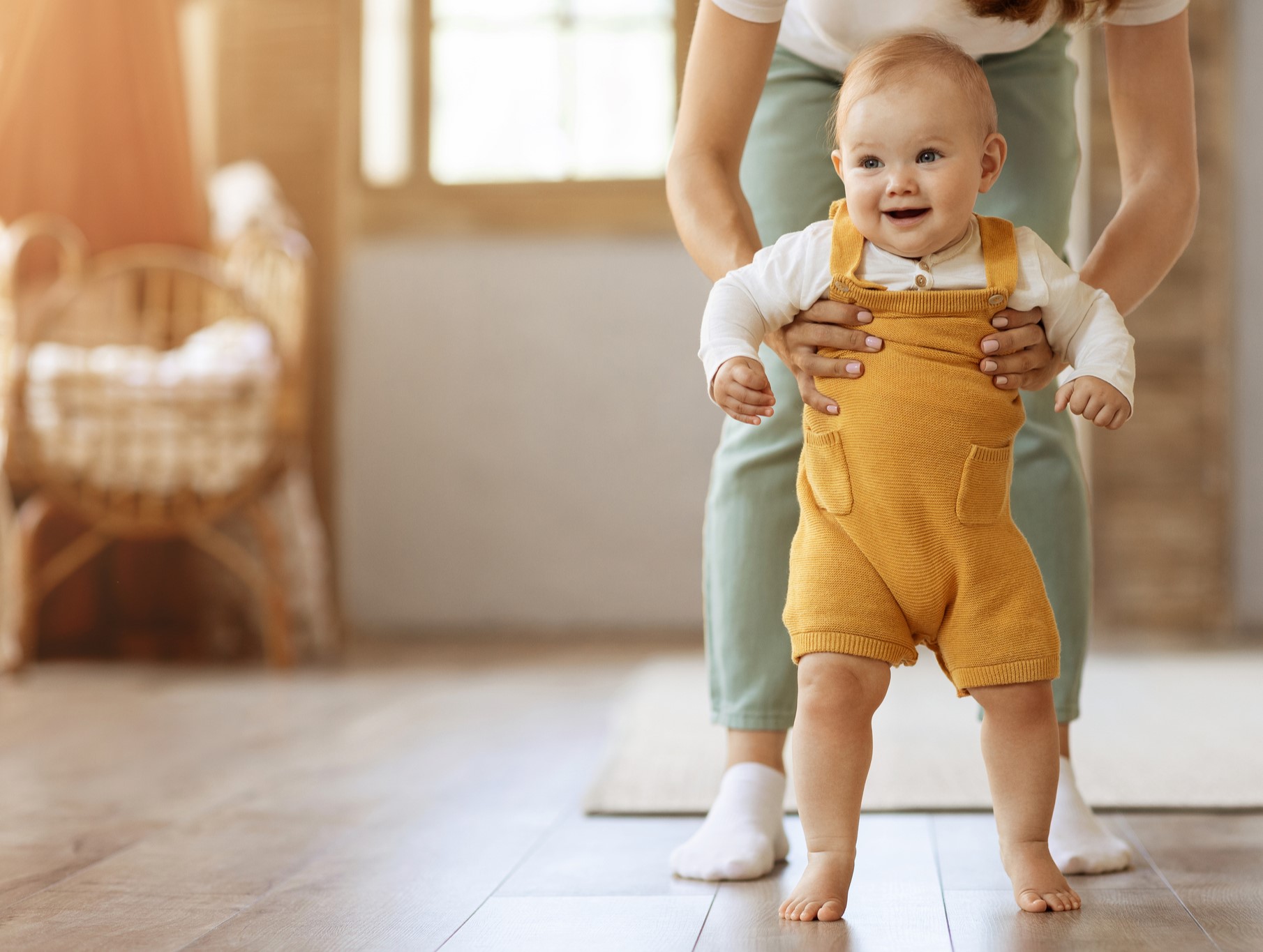 mom holding happy toddler taking first steps