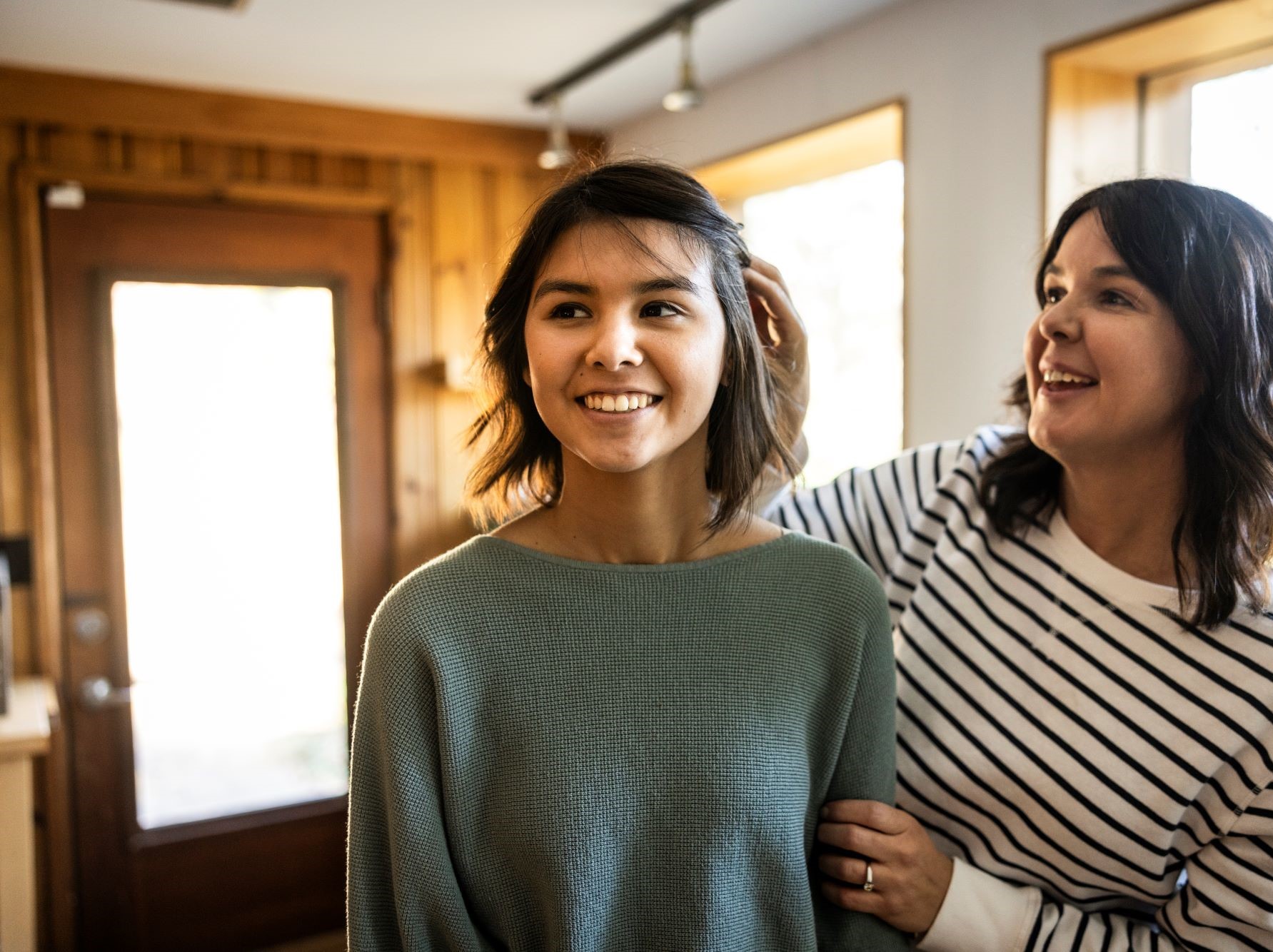 proud smiling mom with arm around her teen daughter