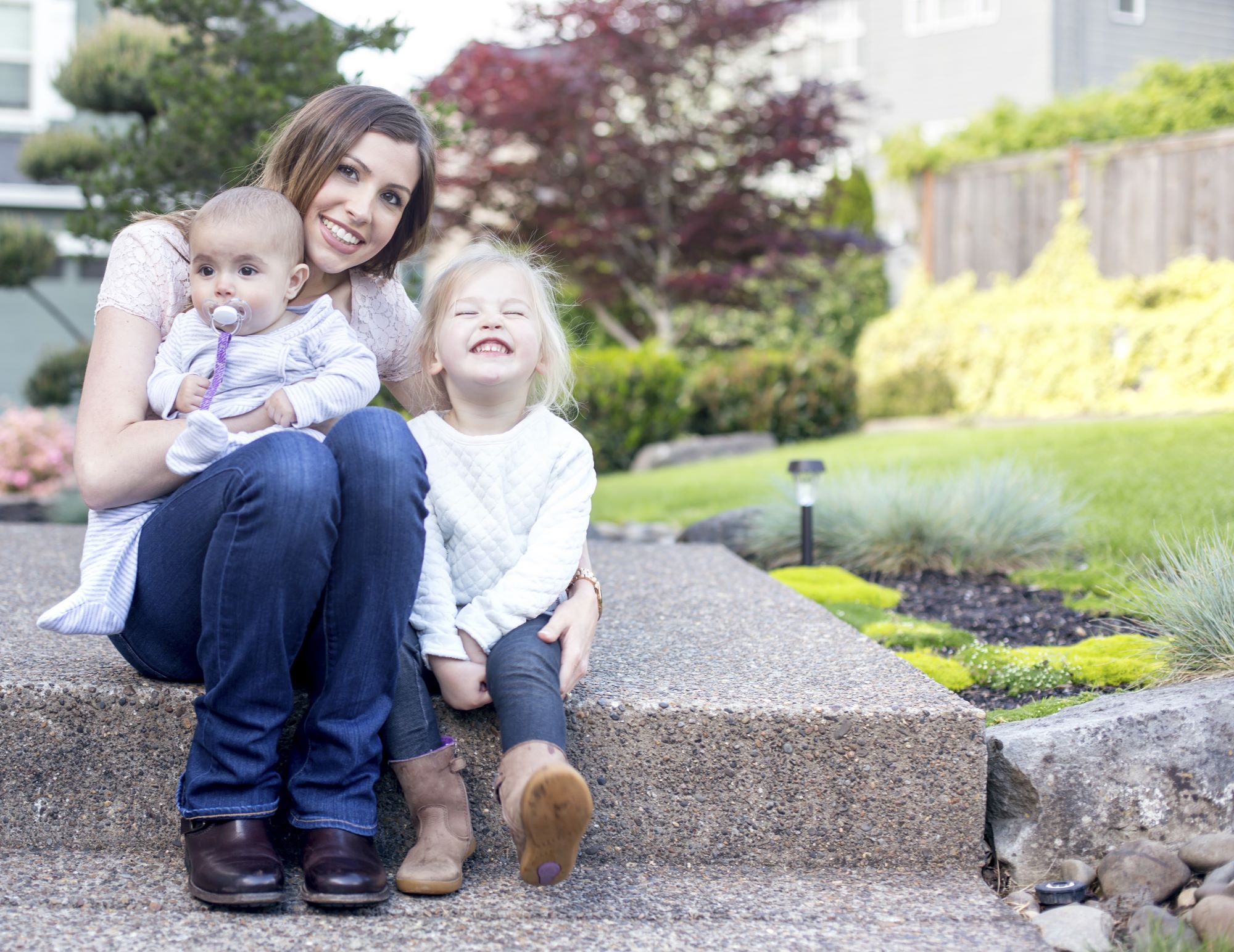 young girl and young woman sitting on a step with a baby in her lap