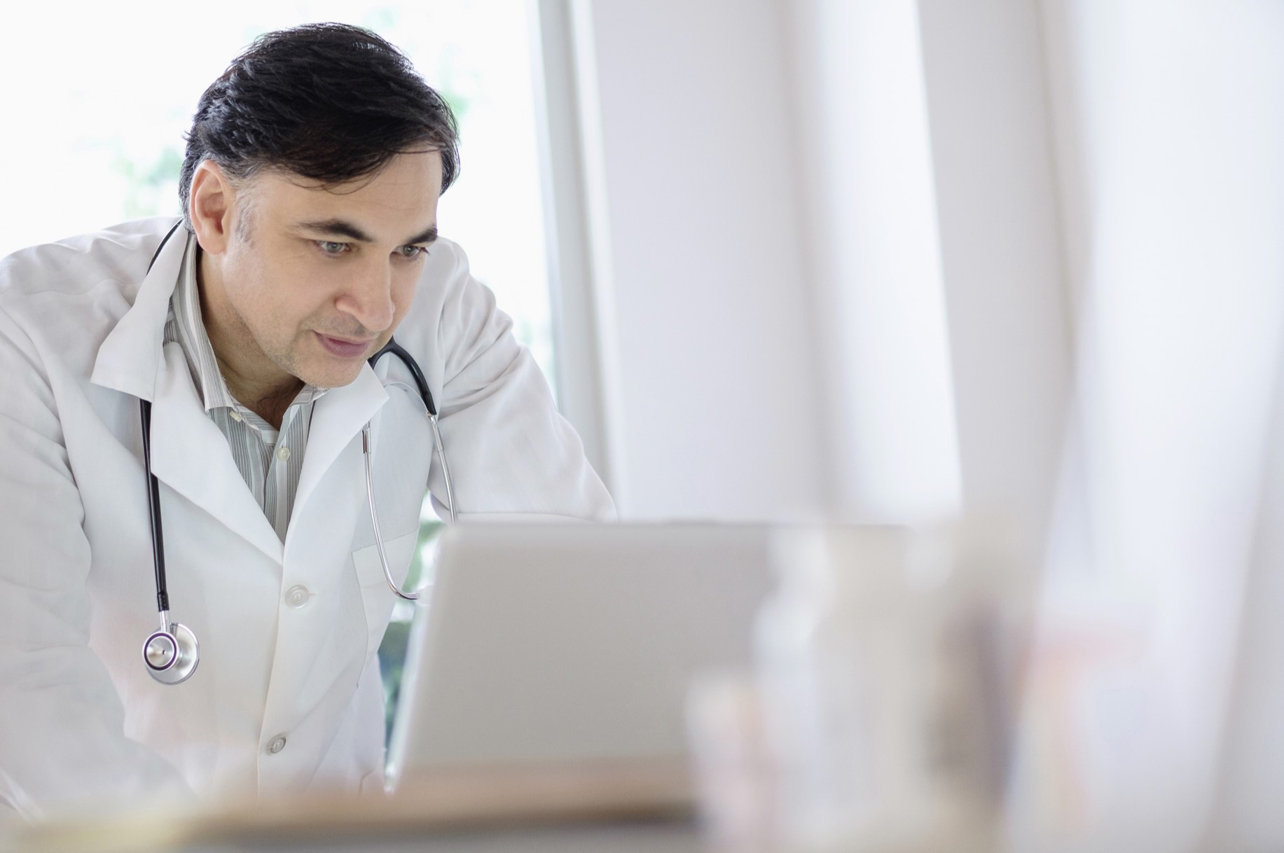 male doctor peering intently at a computer