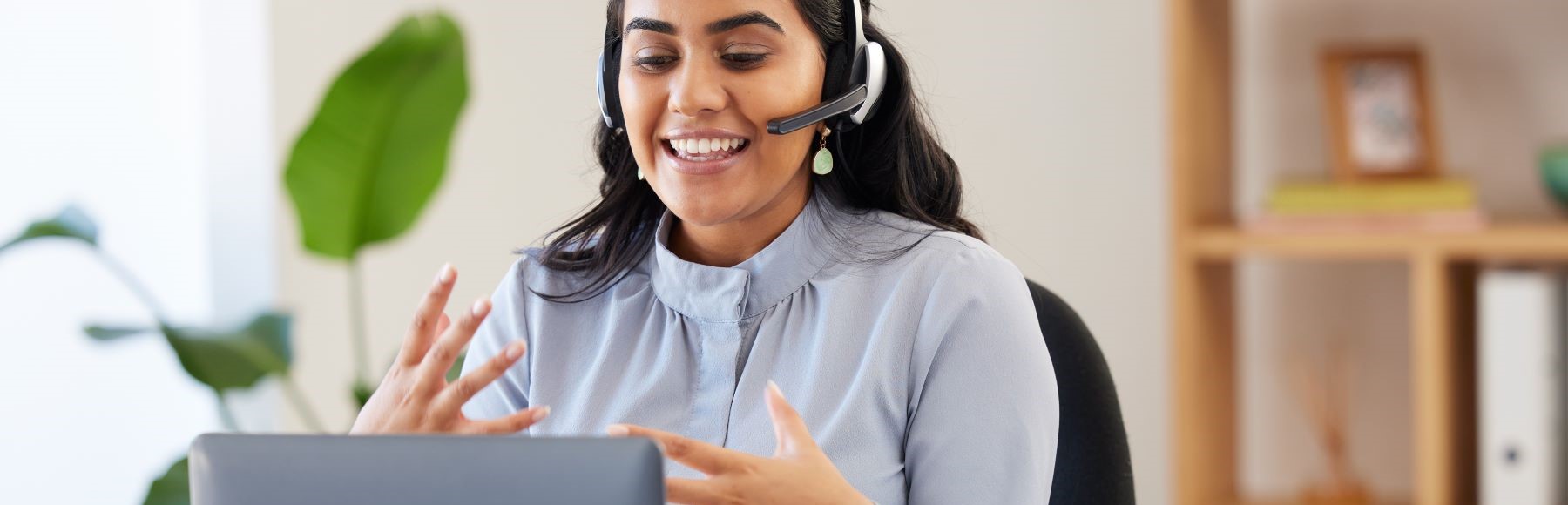 smiling technician with headset working at her computer